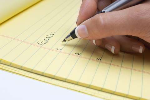 Woman writing list of goals, close-up of hand