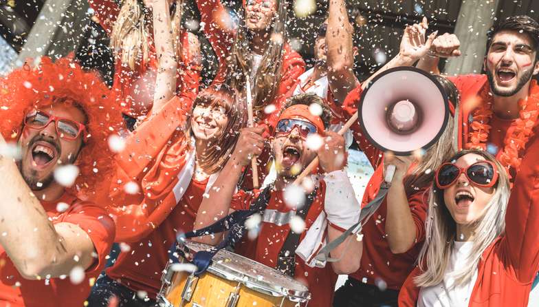 Friends football supporter fans cheering with confetti watching soccer match event at stadium - Young people group with red t-shirts having excited fun on sport world championship concept